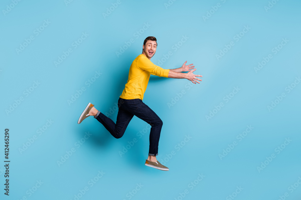 Full length profile portrait of cheerful carefree guy run arms catching good mood isolated on blue color background