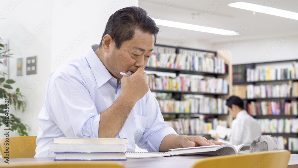 図書館で勉強する中高年男性 図書館で勉強する中高年男性