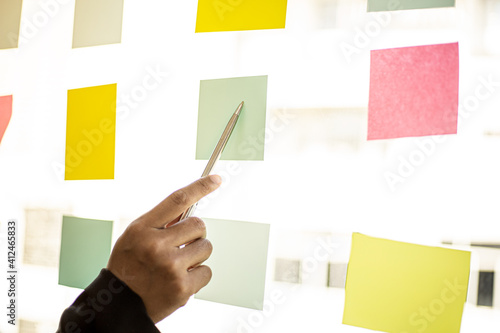 Fotografija Business men are writing on a post-it that is placed in the glass of the conference room to brainstorm the ideas of the operations of the company together to grow the business