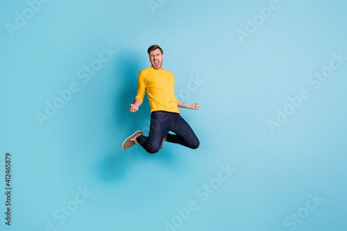 Full length photo of crazy happy man winner jump up air hold fists scream isolated on pastel blue color background