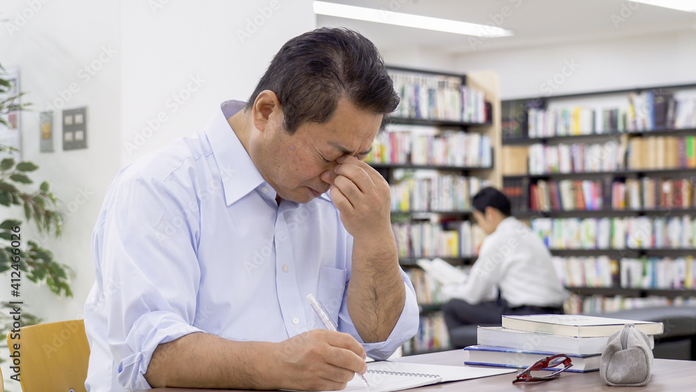 図書館で勉強する中高年男性 図書館で勉強する中高年男性