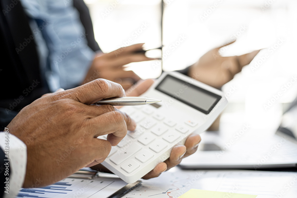 Executives are examining numbers from the company's financial documents with white calculators, a meeting between the executives and the company's finance team meets. Financial concept. Executives are examining numbers from the company's financial documents with white calculators, a meeting between the executives and the company's finance team meets. Financial concept.