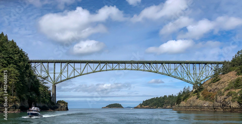 View looking West from boat transiting Deception Pass with bridge above and another boat going by. © Dawn