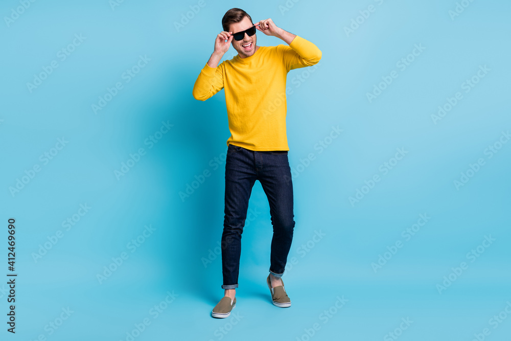 Full size portrait of ecstatic cheerful man hands touch sunglass open mouth isolated on blue color background Full size portrait of ecstatic cheerful man hands touch sunglass open mouth isolated on blue color background