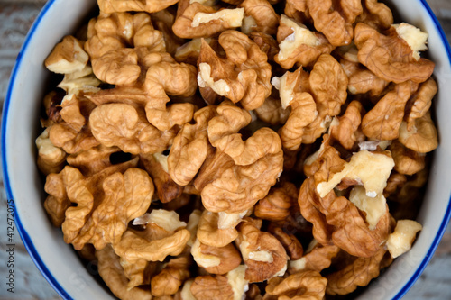 Walnuts. Walnut kernels. Clean organic walnuts. Nuts in the cup on vintage blue wooden background. Walnut tree fresh fall harvest.