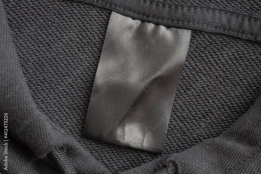 Blank black laundry care clothes label on black fabric texture background Blank black laundry care clothes label on black fabric texture background