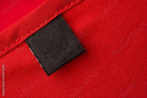 Blank black laundry care clothes label on red fabric texture background