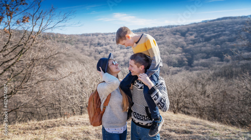 Beautiful happy young family with boy son spending time together in spring forest