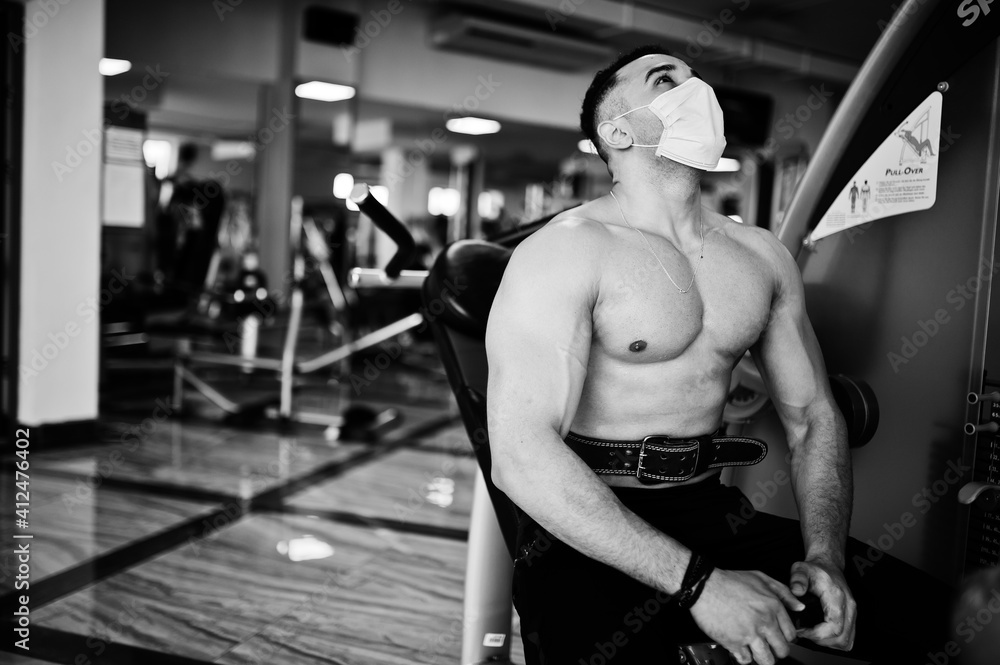 Muscular arab man, wear medical face mask training in modern gym. Fitness arabian men with naked torso doing exercises, durig coronavirus pandemic. Muscular arab man, wear medical face mask training in modern gym. Fitness arabian men with naked torso doing exercises, durig coronavirus pandemic.
