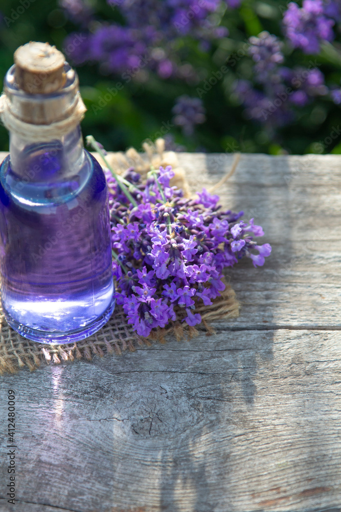 Lavender Essential oil bottle on wood table and flowers field background