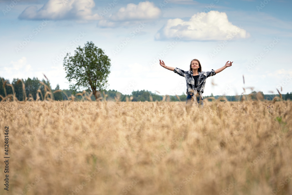 Teenage girl stands with arms up in the wheat field in summer day Teenage girl stands with arms up in the wheat field in summer day