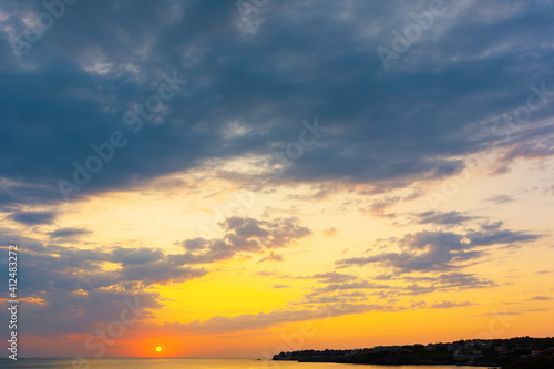 dynamic cloudscape in summer at sunrise. dark clouds on the sky in yellow and pink morning light. dramatic weather condition, picturesque scenery above the sea