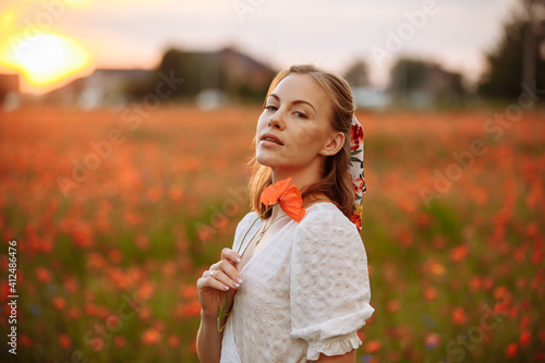 girl in a white dress with a poppy flower in her hands