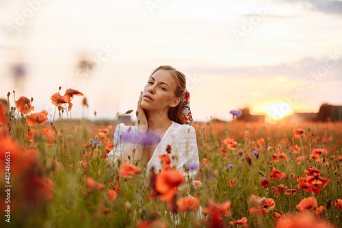 Fototapeta Naklejka Na Ścianę i Meble -  girl in a white dress in a field of poppies on a sunset background