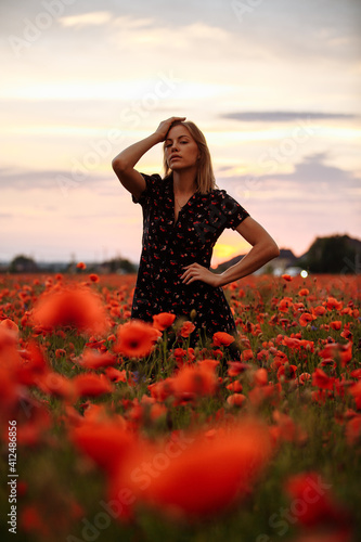 Fototapeta Naklejka Na Ścianę i Meble -  girl in a black dress in a field of poppies