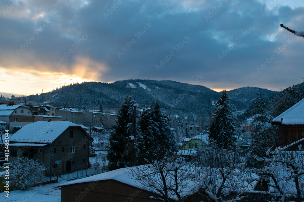Village surrounded by hills in winter during sunset