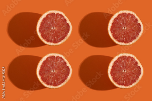 four slices of grapefruit on an orange background. pattern photography