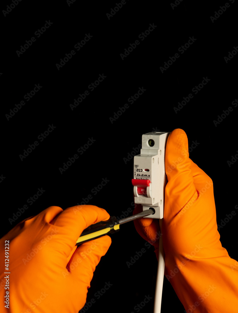 Electrician hands with gloves connect cable to Miniature Circuit Breaker with screwdriver Electrician hands with gloves connect cable to Miniature Circuit Breaker with screwdriver