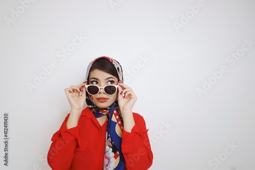 Beautiful woman in retro fashion . Woman in red shirt Sunglasses and blue silk scarf standing over white background.