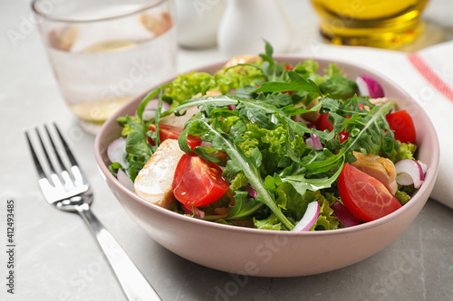 Delicious salad with chicken, arugula and tomatoes on light table, closeup