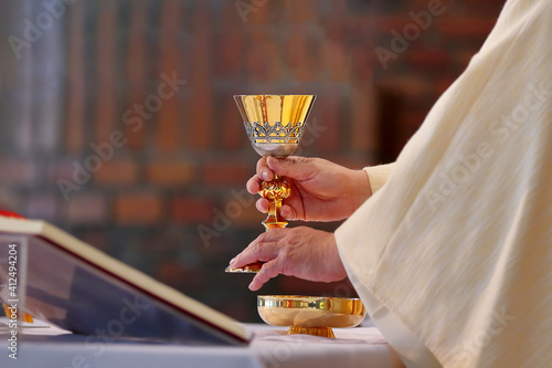 Chalice in the hands of the priest on the altar during the celebration of the mass photo