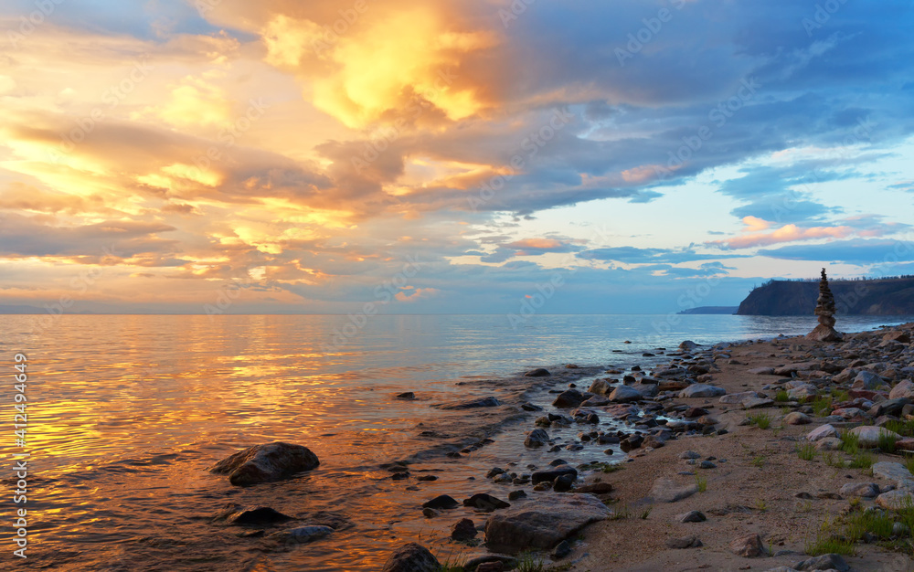 Beautiful landscape with colorful clouds over Lake Baikal in the summer evening. Sandy beach of Olkhon Island at sunset. Natural background. Summer holidays and travel