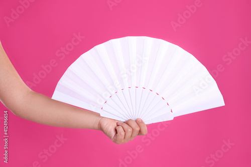 Woman holding white hand fan on pink background  closeup