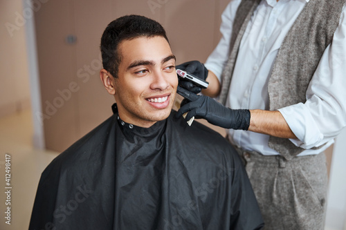 Handsome man relaxing at the beauty procedure in barber shop