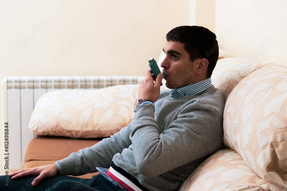 Fototapeta premium young asthmatic taking a bronchodilator because he can't breathe due to coronavirus
