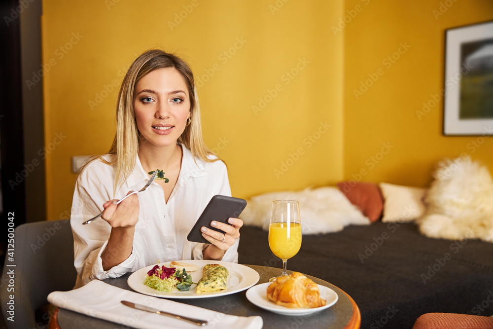 Modern business lady having breakfast in her hotel room