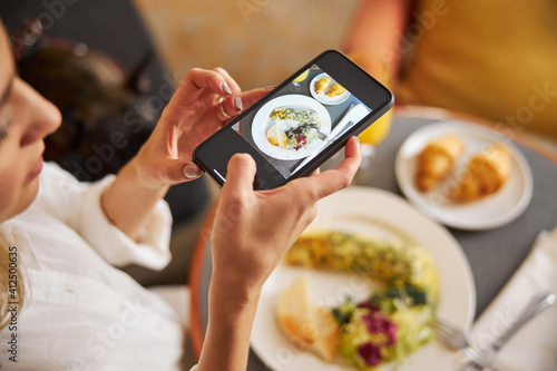 Concentrated lady taking pictures of her breakfast food