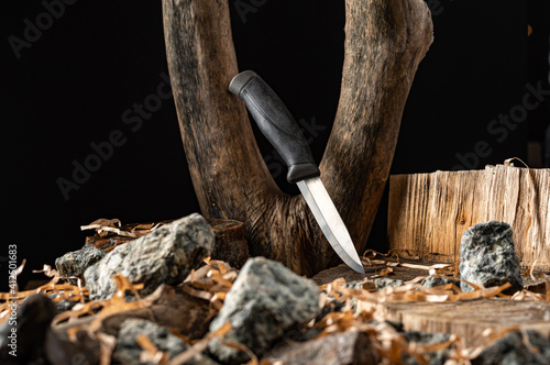 Knife among trees and stones. Knife between wooden stumps. Stylistic composition of the knife.