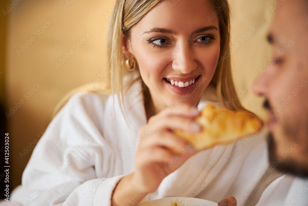 Loving female spouse sharing her croissant with her husband Loving female spouse sharing her croissant with her husband