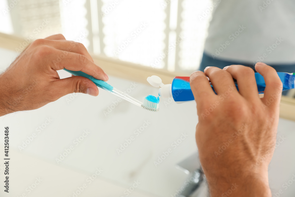 Man applying toothpaste on brush in bathroom, closeup Man applying toothpaste on brush in bathroom, closeup