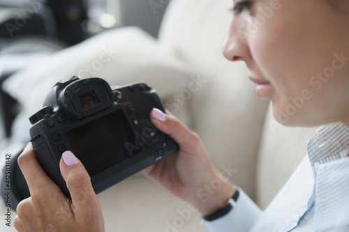 Woman holds black professional camera in her hands. How to become professional photographer yourself from scratch concept