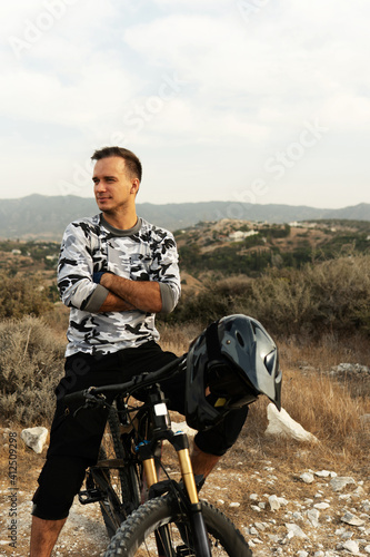 Professional downhill rider with his bicycle on top of mountain