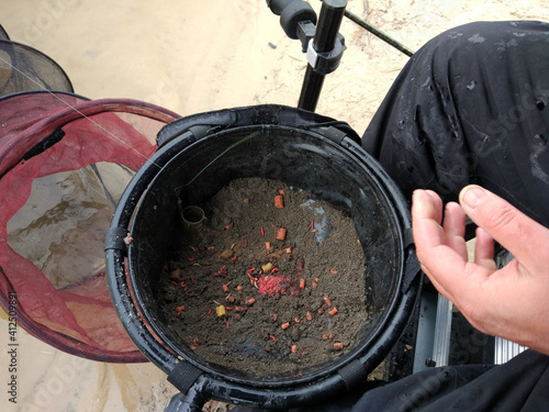Fisherman with a bucket of groundbait for feeder fishing. photo