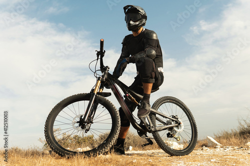 Downhill rider fully equipped with protective gear and his bicycle