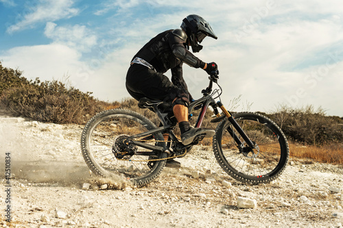 Rider fully equipped with protective gear during downhill ride on his bicycle photo