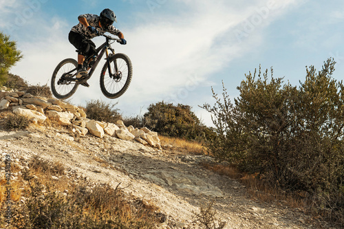 Professional bike rider jumping during downhill ride on his bicycle