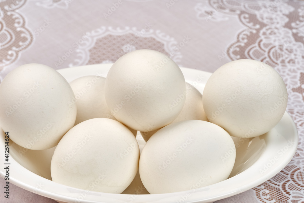 White chicken eggs in a plate on an openwork napkin. Close-up. White chicken eggs in a plate on an openwork napkin. Close-up.