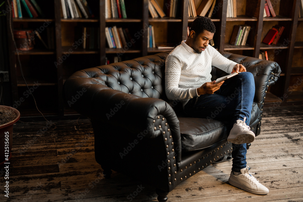 Naklejka premium handsome young african man reading a book 