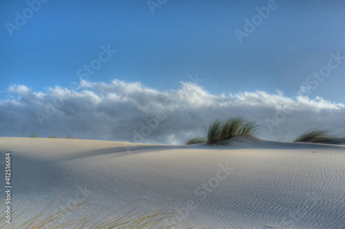 White sand dune with Ammophila grass against blue sky with Stratus clouds at famous Tarifa coast