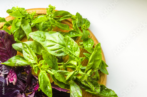fresh green and purple basil leaves for healthy cooking, herbs and spices on wooden cutting board, close-up