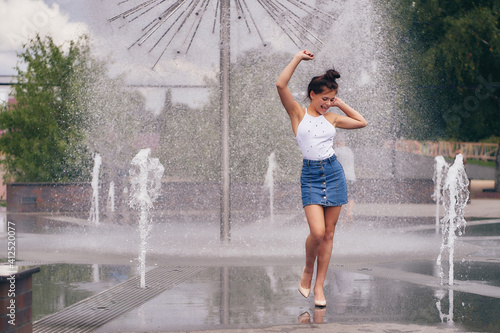 A young attractive woman is having fun on the background of the city fountain.