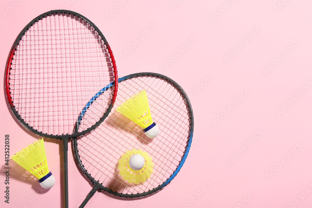 Badminton rackets and shuttlecocks on pink background, flat lay. Space for text