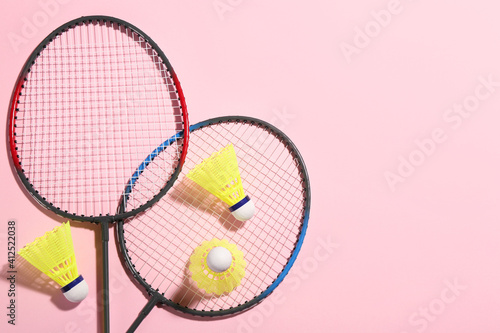 Badminton rackets and shuttlecocks on pink background, flat lay. Space for text © New Africa