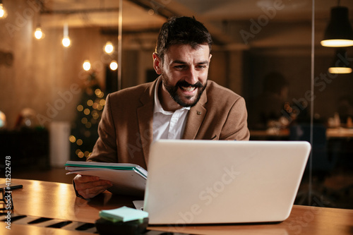 Young businessman using laptop in his office. Businessman taking a notes while working on laptop. photo