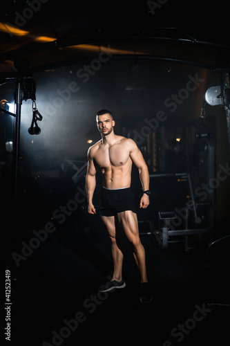 Muscular athlete posing in a dark gym, portrait of a sporty man