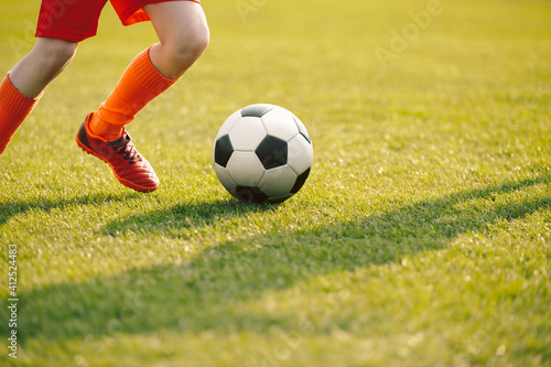 Closeup of Soccer Player Legs in Run. Young Player Running Football Ball on Grass Field. Player in Sports Clothes and Soccer Cleats